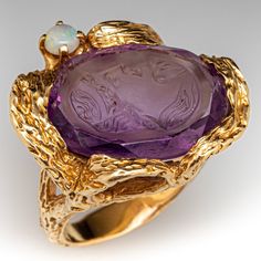 This fabulous ring features a beautifully carved amethyst intaglio set askew within a textured organic semi-bezel. The person depicted in the carving looks up towards a small prong set round opal which accents the design. The wood bark textured ring is crafted in 14k yellow gold and is currently a size 6.75. Extravagant Dresses, Amethyst Rings, Amethyst Cocktail Ring, Amethyst Ring Vintage, Bark Texture, Wood Bark, Amethyst And Diamond Ring, Bold Rings, Textured Ring