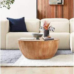 a living room with a white couch and wooden table in front of a wall mounted painting