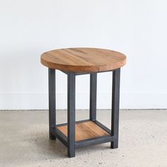 a small wooden table with metal legs and a wood top on concrete flooring area