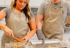 two people in aprons are making food together