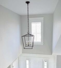 a light fixture hanging from the ceiling in a room with white walls and wood floors