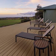 a row of lounge chairs sitting on top of a wooden deck next to a building