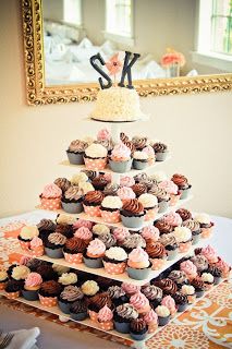 cupcakes are stacked on top of each other in front of a framed monogram