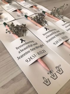 several business cards with pencils and flowers on them sitting on top of a table