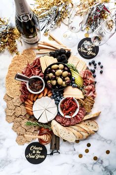 an assortment of cheeses, crackers and meats on a platter with champagne