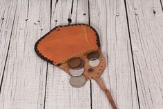 a wooden table topped with lots of coins and a brown leather bag filled with coins