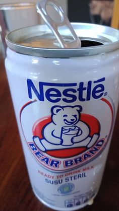 a can of nestle bear brand sitting on a table with a spoon in it