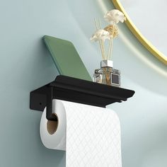 there is a toilet paper holder on the wall with a camera and flowers in it