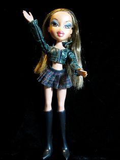 a doll with long hair wearing a skirt and knee high boots, holding her arms up in the air