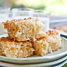 three pieces of coconut cake on a plate with a glass of milk in the background