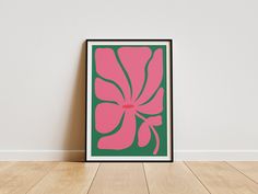 a pink and green flower on a white wall in an empty room with wood flooring