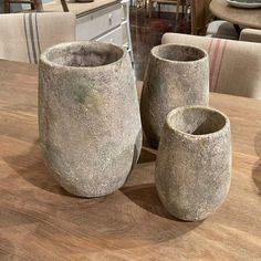 three cement vases sitting on top of a wooden table next to chairs in a living room