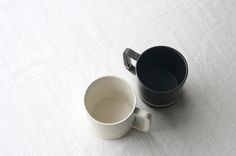 two coffee cups sitting on top of a white table