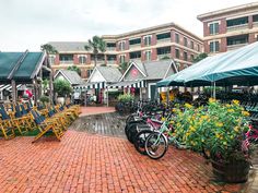 several bicycles are parked in front of some buildings with umbrellas and chairs around them