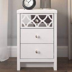 a white nightstand with a clock on top of it