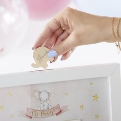 a woman's hand holding a wooden elephant ornament in a white box