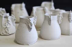 several white vases sitting on top of a table next to each other in different shapes and sizes