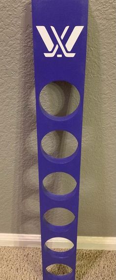 a blue rack with several holes in it on the floor next to a gray wall