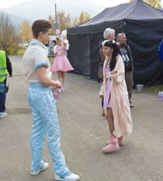 a man and woman in costume standing next to each other on a street near tents