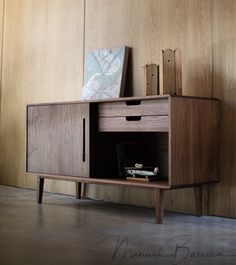 a wooden cabinet sitting next to a wall with a painting on it's side