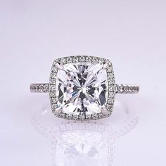 a cushion cut diamond ring with pave set diamonds on the band and sidestones