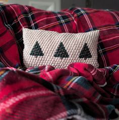 a red and black plaid couch with christmas trees on the pillow in front of it