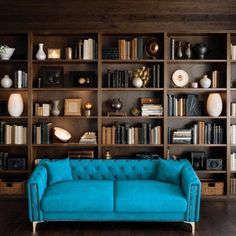 a blue couch sitting in front of a bookshelf