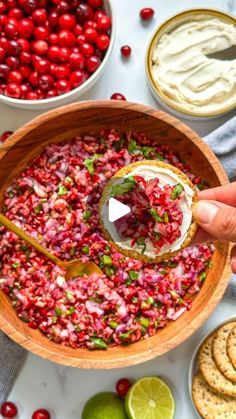 a bowl filled with cranberry salsa surrounded by crackers and limes