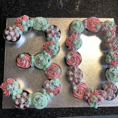 cupcakes arranged in the shape of the letter e on a baking sheet with pink and green frosting