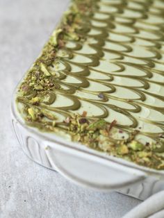 a close up of a cake in a white container on a table with green icing