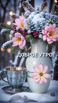 a white vase filled with pink flowers next to a cup on top of a table