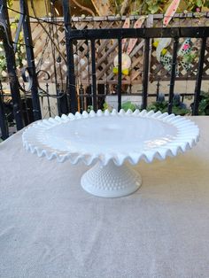 a white cake plate sitting on top of a table next to a black iron fence