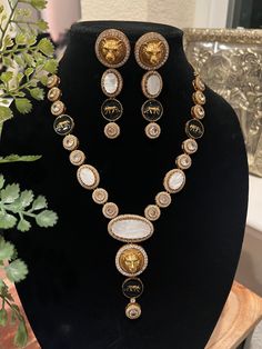 Elevate your ethnic ensemble with this exquisite Sabyasachi-inspired contemporary necklace set, meticulously crafted to honor Indian artistry and tradition. This stunning piece features intricate polki work, accentuated by the radiant beauty of Monalisa stones that cast a mesmerizing glow, and the lion motifs. The necklace boasts an antique gold finish, lending an heirloom-like charm to the design. Each element is expertly outlined with micro American Diamond (AD) stones, adding a touch of brilliance that catches the light from every angle. The centerpiece of the necklace features an ornate design inspired by traditional Indian motifs, showcasing the intricate craftsmanship and attention to detail. The matching earrings complete the set, creating a harmonious and regal look. Polki Necklace Set, Indian Motifs, Radiant Beauty, Contemporary Necklace, Polki Necklace, Ornate Design, Classic Jewelry, American Diamond, Choker Necklaces