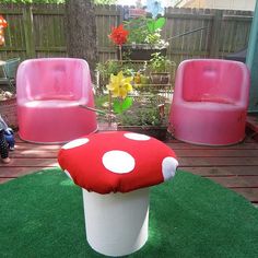 a mushroom shaped bench sitting on top of a grass covered ground next to pink chairs