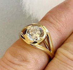 a woman's hand holding a yellow gold ring with a diamond in the center