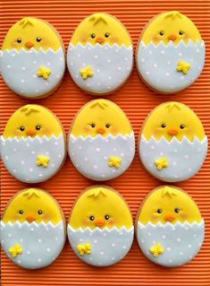 twelve decorated cookies in the shape of ducks with stars on them, sitting on an orange surface