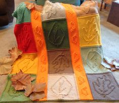 a crocheted blanket sitting on top of a floor next to a pile of leaves