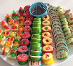 a white plate topped with lots of different colored donuts and pastries on top of each other