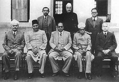 a group of men sitting next to each other in front of a building