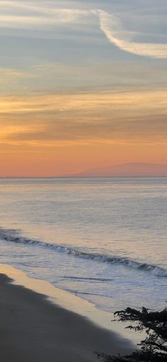 two people walking on the beach at sunset