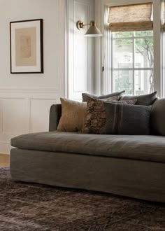 a couch sitting in front of a window next to a rug