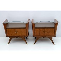 a pair of nightstands with glass top and wooden legs, each side by side