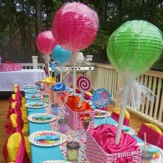 a table set up for a birthday party with paper lanterns, candy bars and lollipops