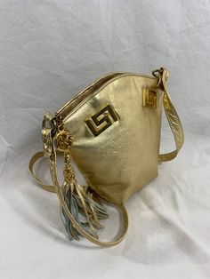 Measurements are 9"2 wide, 8"6 high, 3"5 deep with and a  46" shoulder strap with a 21" drop. On the interior there is one main compartment lined in fabric, back zipper pocket and a top zipper closure. Bag is adorned with gold tone hardware, exterior zipper pocket and a nice tassel. There are a few light scuffs along with minor chipping on gold tone pull tab hardware. This is a lovely vintage gold metallic leather  bag and can be used crossbody.  I want to stress that item is vintage which means Gold Leather Shoulder Bag With Brass Hardware, Gold Shoulder Bag With Brass Hardware For Travel, Gold Crossbody Shoulder Bag With Brass Hardware, Gold Bag With Brass Hardware For Everyday Use, Gold Shoulder Bag With Brass Hardware For Everyday Use, Everyday Gold Shoulder Bag With Brass Hardware, Gold Rectangular Bag With Brass Hardware, Gold Bags With Brass Hardware, Rectangular Shape, Gold Rectangular Bags With Brass Hardware