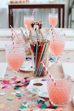 the table is set with glasses, cups and confetti sticks for party guests