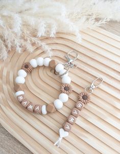 a pair of earrings sitting on top of a wooden table next to a white feather