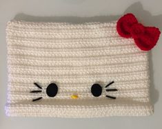 a crocheted hello kitty hat with a red flower on it's head