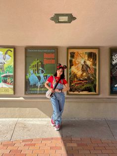 a woman standing in front of posters on the side of a building and holding a camera