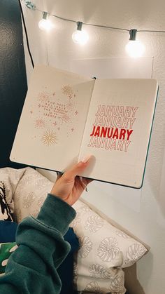 a person holding up an open book with the words january and january written on it