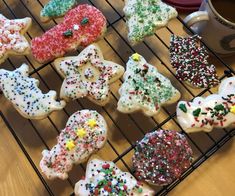 several decorated cookies on a cooling rack next to a cup of coffee